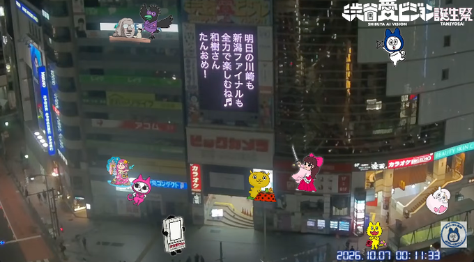 A nighttime livestream view of a city street with cartoon mascot stickers overlaid; Japanese text in the top right reads '渋谷愛ビジョン観察 SHIBUYA & VISION TANIYOSAS' and a timestamp shows '2026.10.01 00:11:33'.