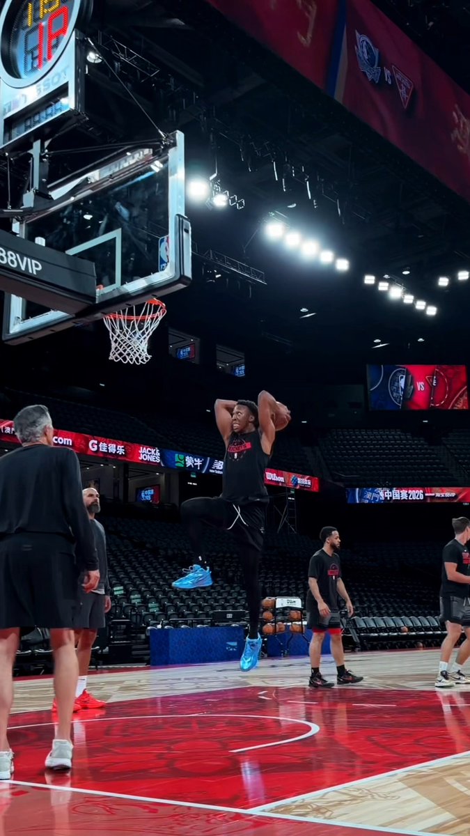 A basketball player leaps high near the hoop during a pre-game warmup in an empty arena, with visible signage reading "JP TISSOT," "88VIP," and "JACK & JONES," suggesting the team is counting down the days to tip-off of the season opener.