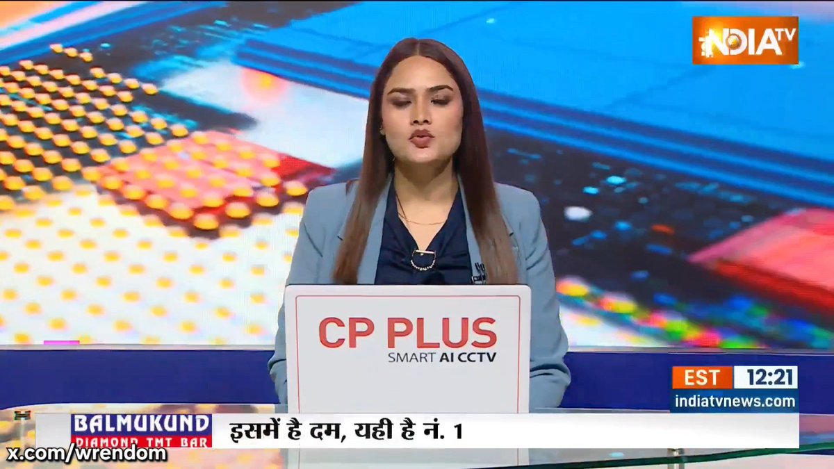 A female news anchor on India TV speaks from behind a 'CP PLUS Smart AI CCTV' laptop, with Hindi text on a lower third banner and an 'EST 12:21' timestamp.