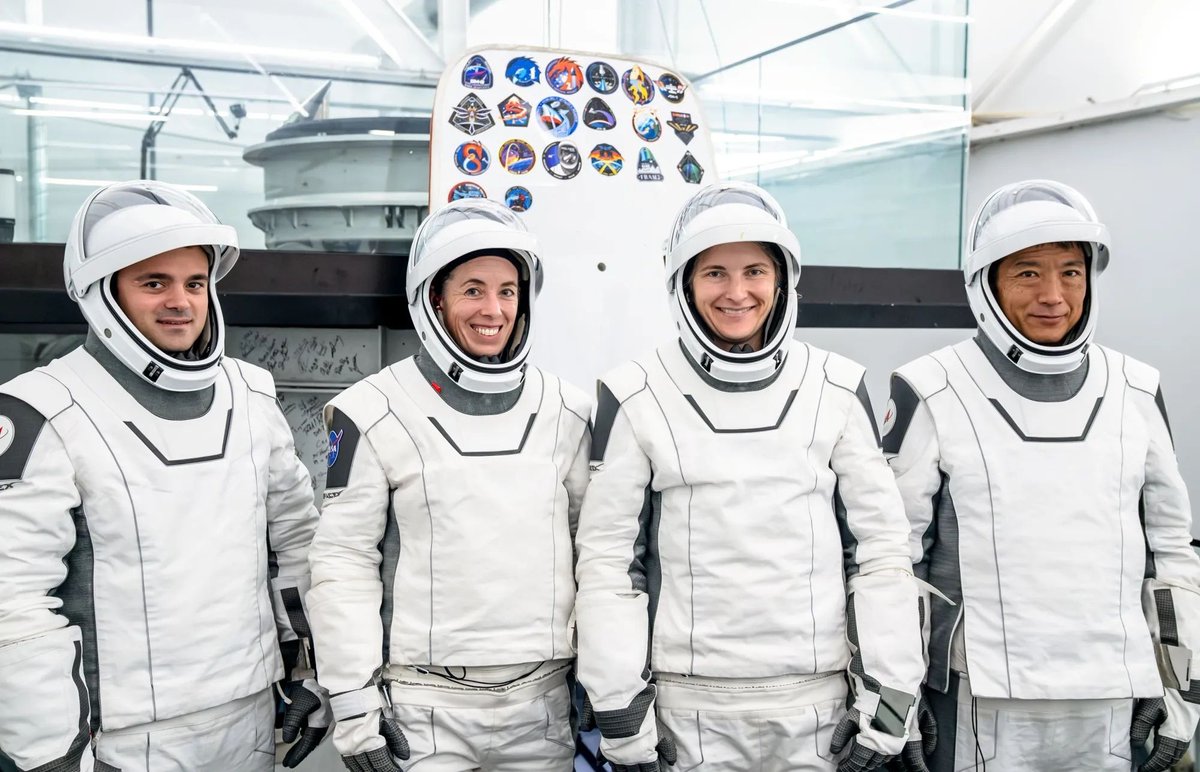 The four members of NASA's SpaceX Crew-14 mission stand in their flight suits, white with black trim, and smile at the camera. Credit: SpaceX