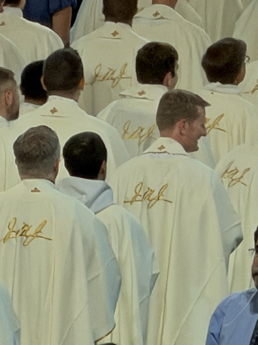 thattradgal's tweet photo. Look closely at the priests’ vestments from Fulton Sheen’s beatification.

On the back of every one was embroidered:

JMJ

It was Fulton Sheen’s signature.

Whenever Sheen stepped before the cameras for Life Is Worth Living, he would begin by writing “JMJ” at the top of his famous blackboard.

Three letters.

Three names.

The entire foundation of his ministry.

And now, at the Mass where the Church officially declared him Blessed Fulton Sheen, 1,000 priests wore those same initials on their backs.

The man who spent his life proclaiming Jesus, loving Mary, and entrusting himself to St. Joseph was honored with those same three names surrounding the altar.

JMJ.

Jesus. Mary. Joseph.