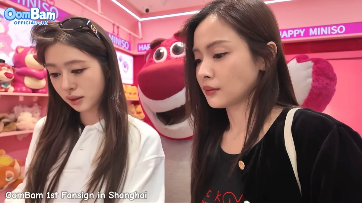 Two young women stand in a Miniso store with a pink fox mascot behind them; text on screen reads 'OomBam OFFICIAL CH3' and 'OomBam 1st Fansign in Shanghai'.