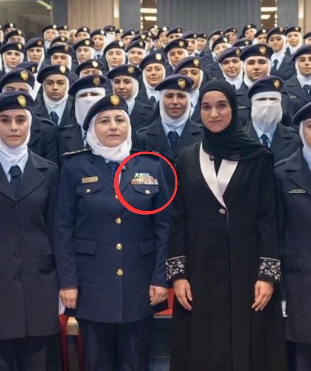 karimfranceschi's tweet photo. The YPJ is still patiently waiting for a phone call from the al-Qaeda Ministry of Interior. Meanwhile, mashallah, look at the chief of police, could she have racked up all those medals in the last two years? Or did she get retroactive medals from her time running the Al-Khansaa Brigade, responsible for policing women’s attire and enforcing Sharia law? 

In cities like Raqqa, they also managed the auctioning of Yazidi girls sold into slavery and subjected to sexual violence and rape, both lawful under Salafi-jihadist doctrine.