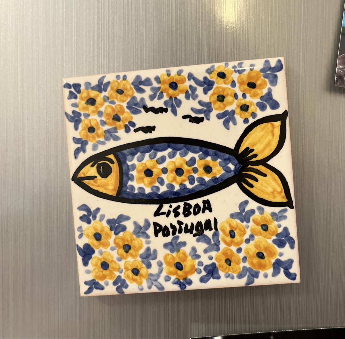 O_chandesu1's tweet photo. リスボンのサンデーマーケットにて、おばあちゃんが一人でぽつんと手工芸品を売っていた。ふと目をやると、このマグネットの魚に眉毛があることに気付いて急にきゅんと胸がトキめいた。「Hola, これはあなたの手作り？」と聞くと、はいと言うので、「この魚には眉毛があるよ！！すごく良い！！」と伝えたら、嬉しそうにニコ☺️っと笑ってくれた。この手のマグネットはその辺のお土産屋で大量生産されたものがたくさんあるんだけど、おばあちゃんの手作り(裏にはおばあの名前入���)でしかも魚に眉毛を描いていることが素晴らしすぎて購入しました。その国に行ったことを証明するものより、心がトキめいたものを買うこそ価値があるし、今後ずっと大事にできるんだよね。