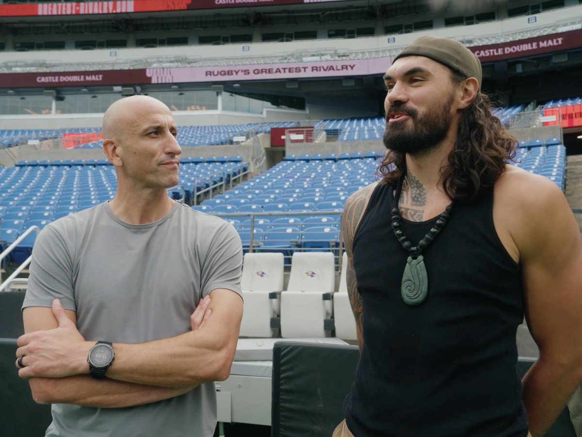 Actors Dwayne Johnson and Roman Reigns stand in an empty stadium in a scene from a wrestling-related production.
