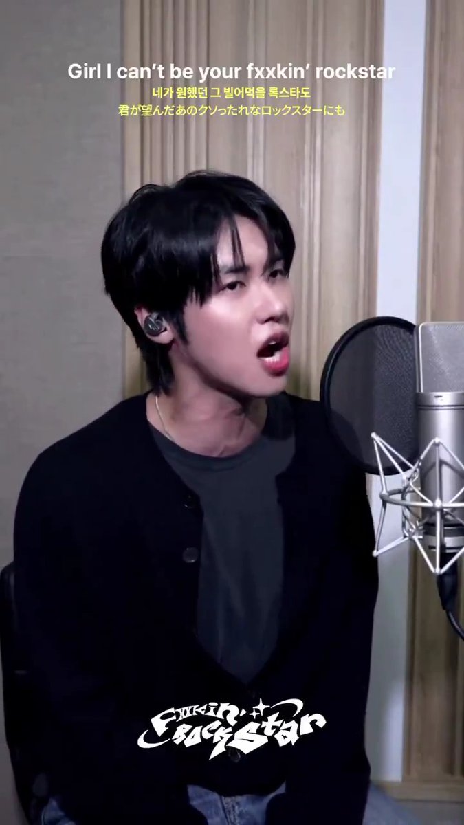 A young man with dark hair sings into a studio microphone, with on-screen lyrics reading "Girl I can't be your fxxkin' rockstar" along with Korean and Japanese translations.
