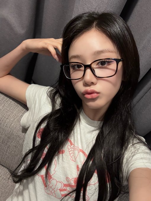 A duplicate of the previous selfie-style portrait of the woman with black hair, glasses, and a white t-shirt.