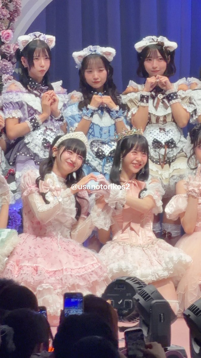 Five young women in elaborate frilly Lolita-style dresses and animal-eared headpieces pose on stage, with two in the front (one wearing a crown) forming heart shapes with their hands. The watermark "@usanotorikos2" is visible across the image, connecting to the "あにまるず" (Animals) post theme reflected in the performers' cat/bear ear accessories.