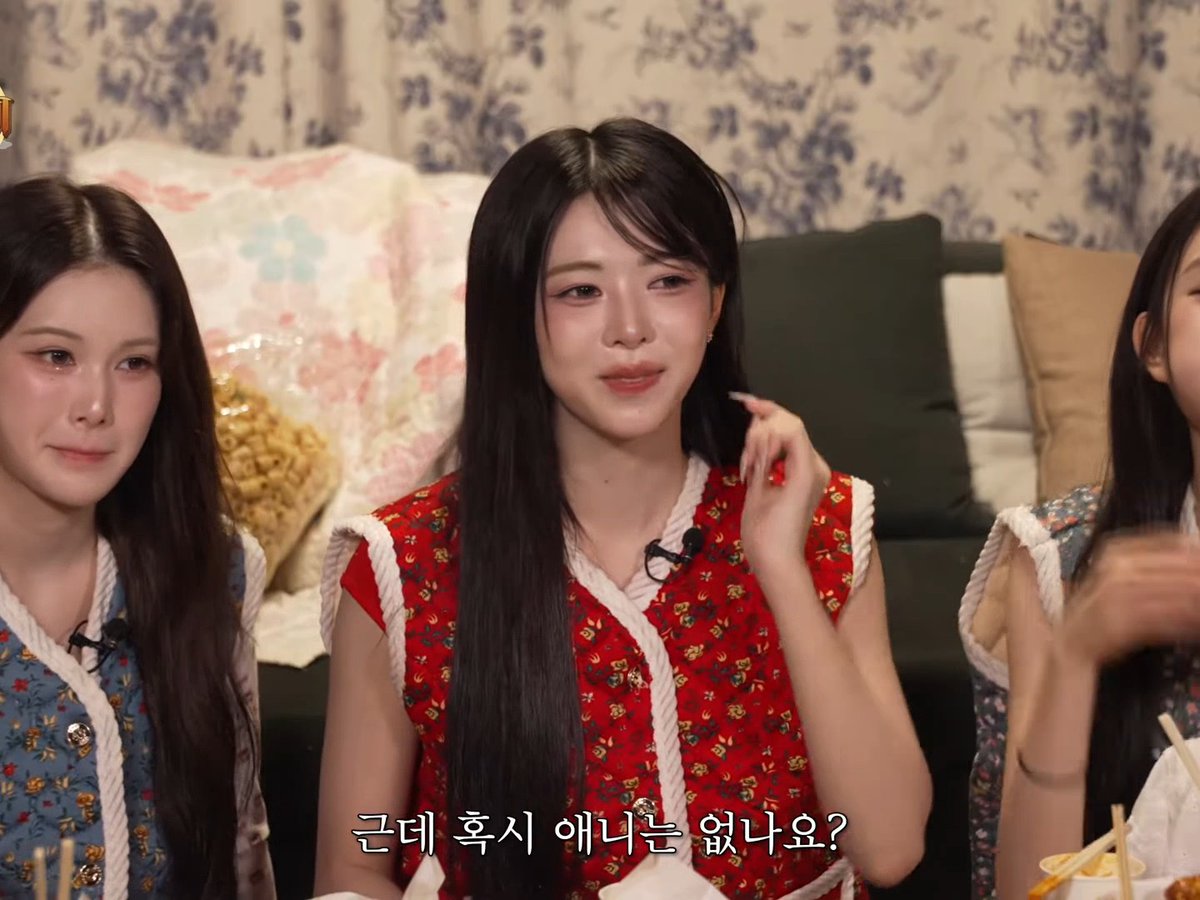 Three young women in floral tops appear to be on a TV show or interview, with the center woman in red speaking; Korean subtitles read '근데 혹시 아니었나요?' (But maybe not?).