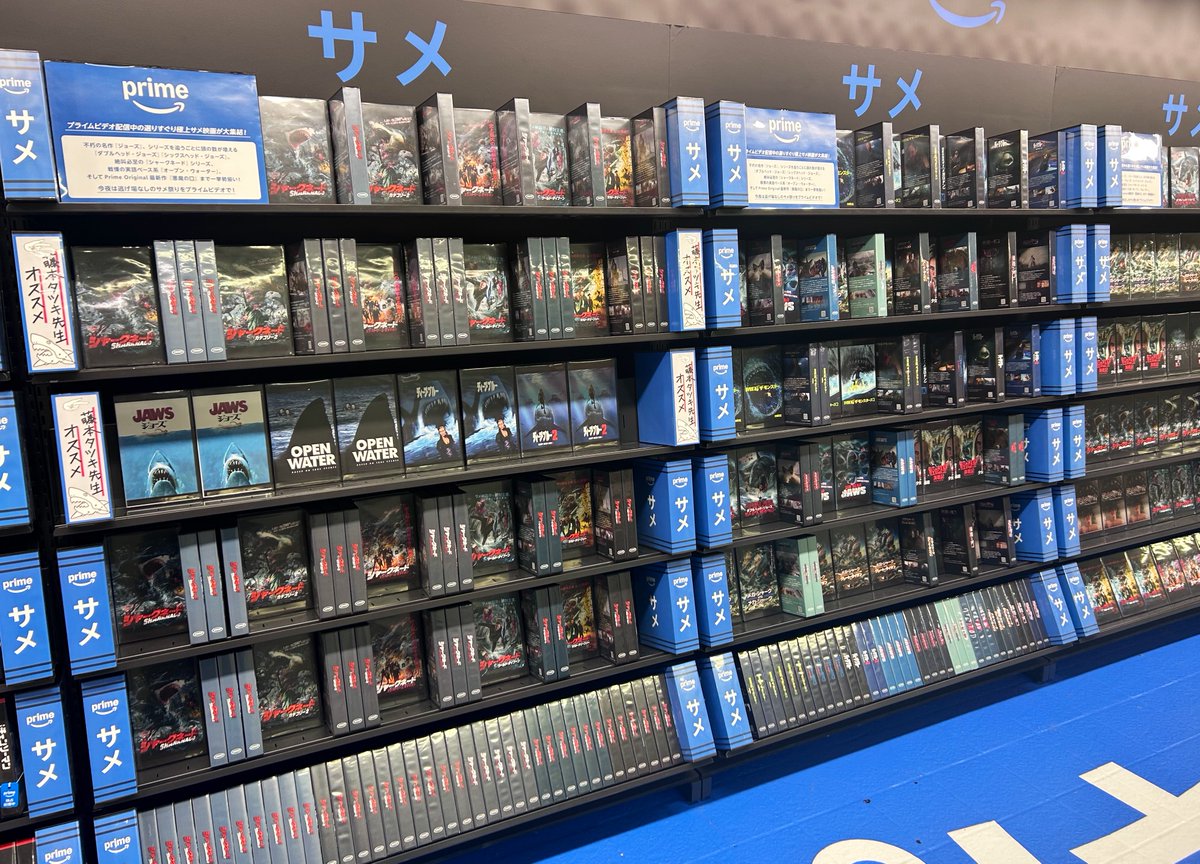 cccutthecrap's tweet photo. 新宿駅のチェンソーマンの広告神だった。レンタルビデオショップに見立てて実在のサメ映画とパロディ並べて、ビデオは実際に手に取れる🦈📼 https://t.co/OoNCAiW4AJ