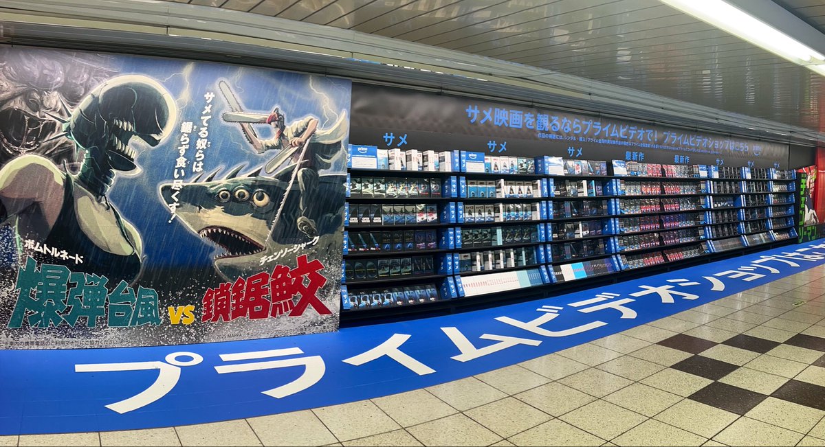 cccutthecrap's tweet photo. 新宿駅のチェンソーマンの広告神だった。レンタルビデオショップに見立てて実在のサメ映画とパロディ並べて、ビデオは実際に手に取れる🦈📼 https://t.co/OoNCAiW4AJ
