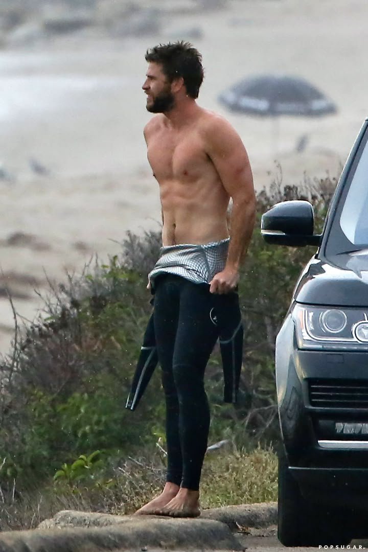 dorawhite47's tweet photo. actor Liam Hemsworth stripping out of a wetsuit on a beach close to a car ... https://t.co/x1YhXra22P