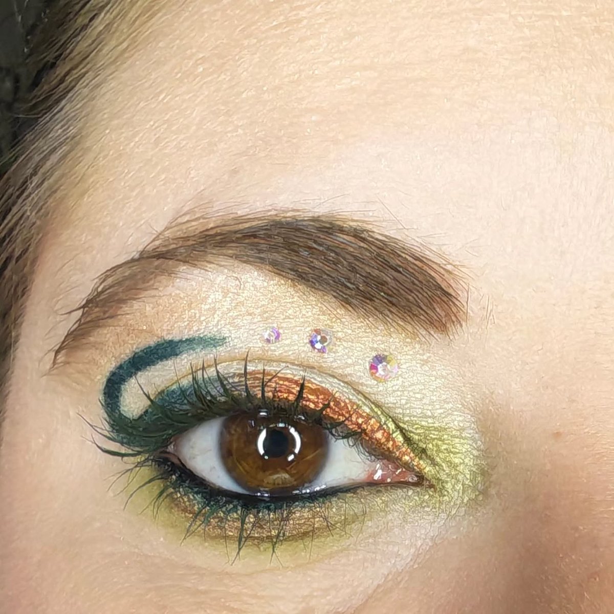 IanKozatek's tweet photo. Éclat sauvage : reflets dorés, vert intense et touches scintillantes pour capter la lumière. Un maquillage créatif et audacieux, pensé pour exprimer sa personnalité sans limites. https://t.co/ViNWtU41Lr