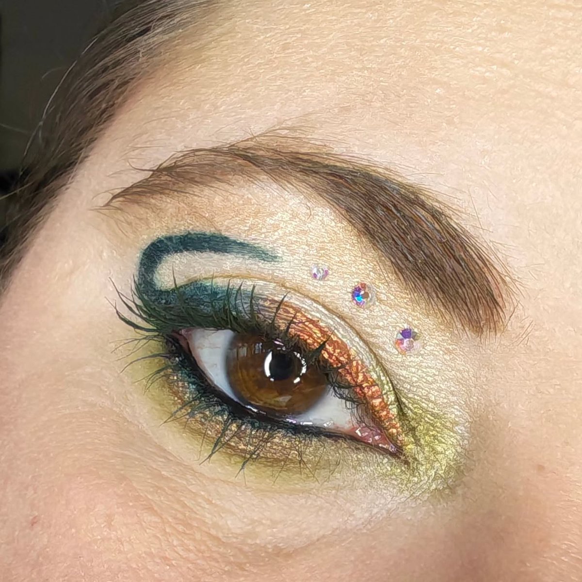 IanKozatek's tweet photo. Éclat sauvage : reflets dorés, vert intense et touches scintillantes pour capter la lumière. Un maquillage créatif et audacieux, pensé pour exprimer sa personnalité sans limites. https://t.co/ViNWtU41Lr