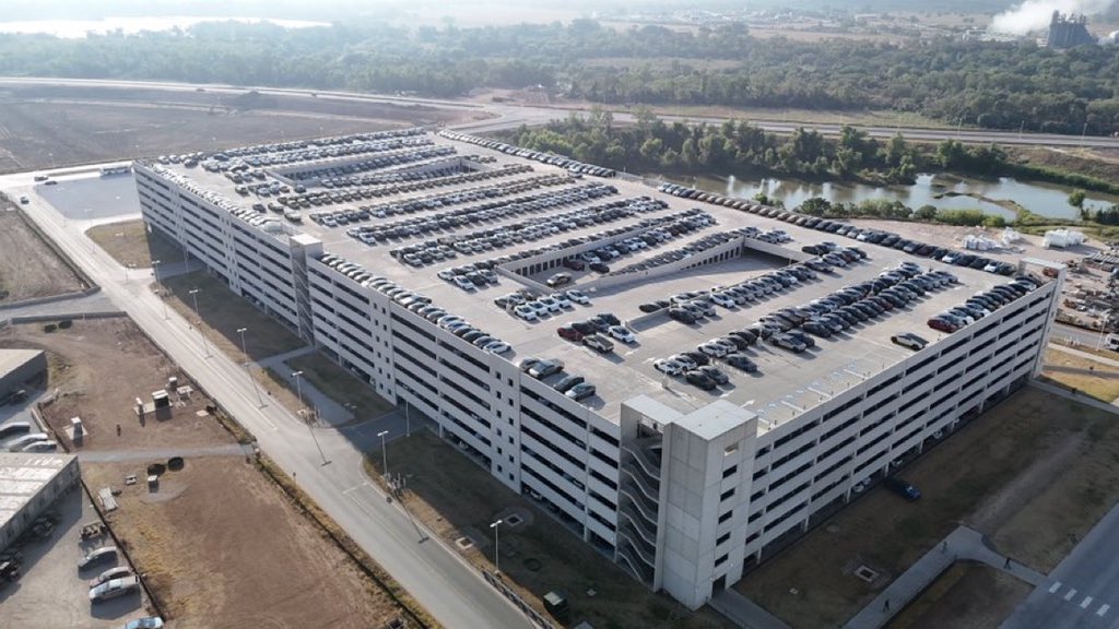 JoeTegSpaceX's tweet photo. This is something new, at least at this SCALE, at Giga Texas … hundreds of vehicles, Model Y’s, @cybertruck &amp; Cybercabs being move from the W outbound lot to the E parking garage, filing up inside and on the roof! https://t.co/4NbOuujROz