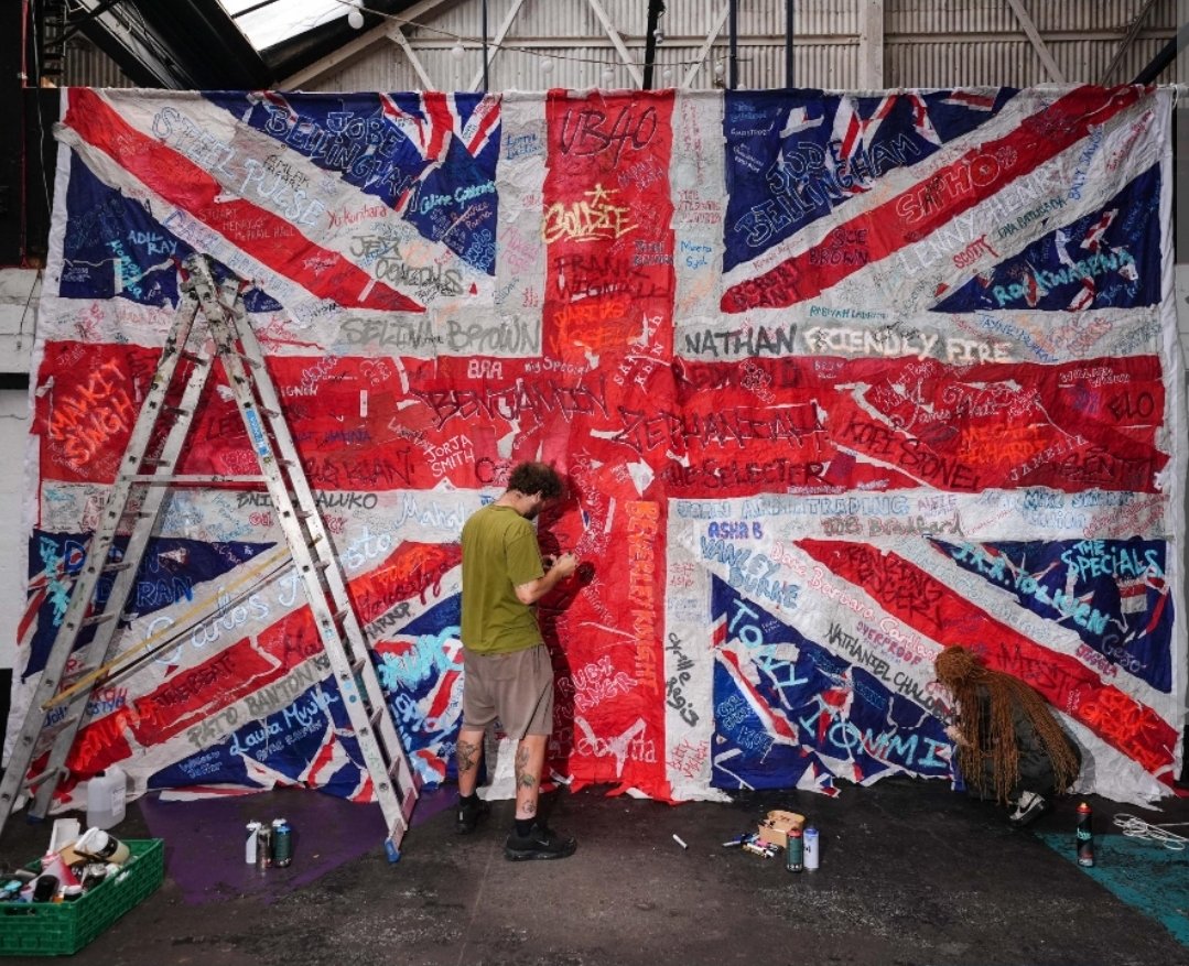 I_amMukhtar's tweet photo. A Birmingham artist has created a huge Union Jack from tatty lamppost flags, featuring signatures from influential people from Birmingham and the surrounding areas.

The artist, Clare Elisabeth, calls the piece “Re-Union Jack”.
Ryan Bridge made a video about it, and he is absolutely fuming.