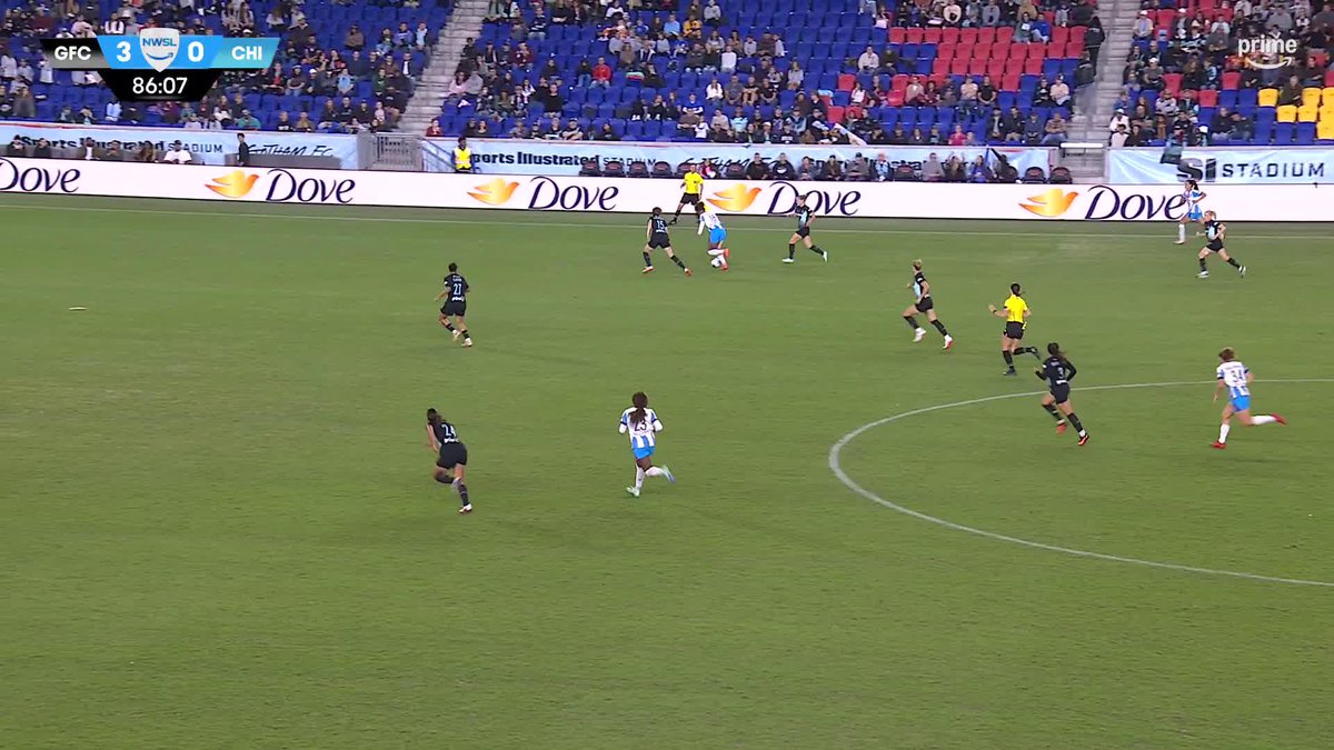 The image shows an NWSL match between GFC and CHI at 86:07 with GFC leading 3-0, though the caption suggests Tessa Dellarose had just scored for Chicago to make it 3-1, contradicting the visible scoreboard. Players in dark and light blue kits are seen advancing on the pitch with Dove advertising boards and Sports Illustrated Stadium signage visible in the background.