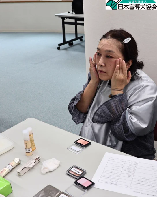 参加者が両手を使いながら左右の頬の位置を確認し、チークを塗っている様子。