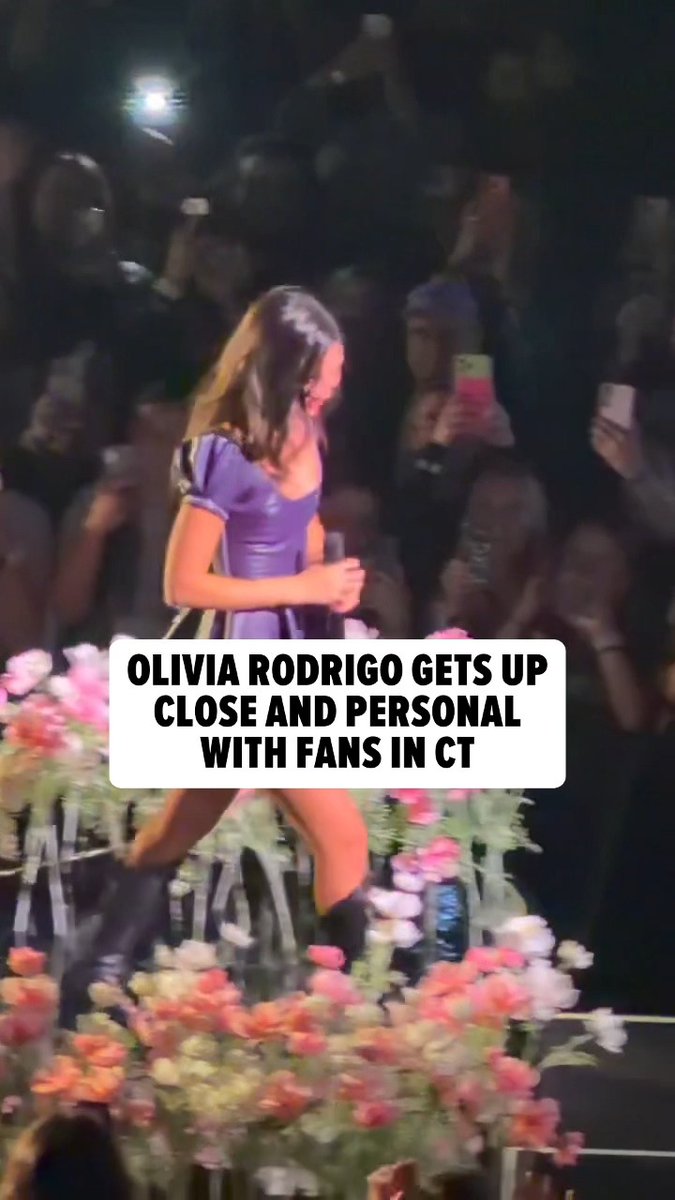 Olivia Rodrigo, wearing a purple dress, is shown interacting with fans at the front row of her concert. The image includes overlaid text that reads "OLIVIA RODRIGO GETS UP CLOSE AND PERSONAL WITH FANS IN CT."