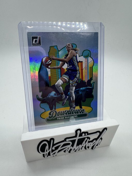 A Donruss Downtown Paige Bueckers basketball trading card in a protective case on a display stand, featuring a buffalo design and an autograph plaque.
