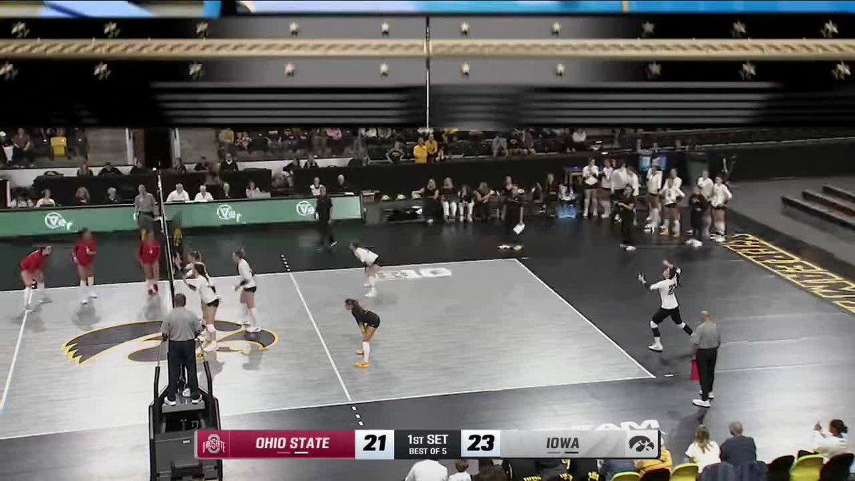 A volleyball match between Ohio State (21) and Iowa (23) in the 1st Set, played on a court marked with the Iowa Hawkeyes logo.