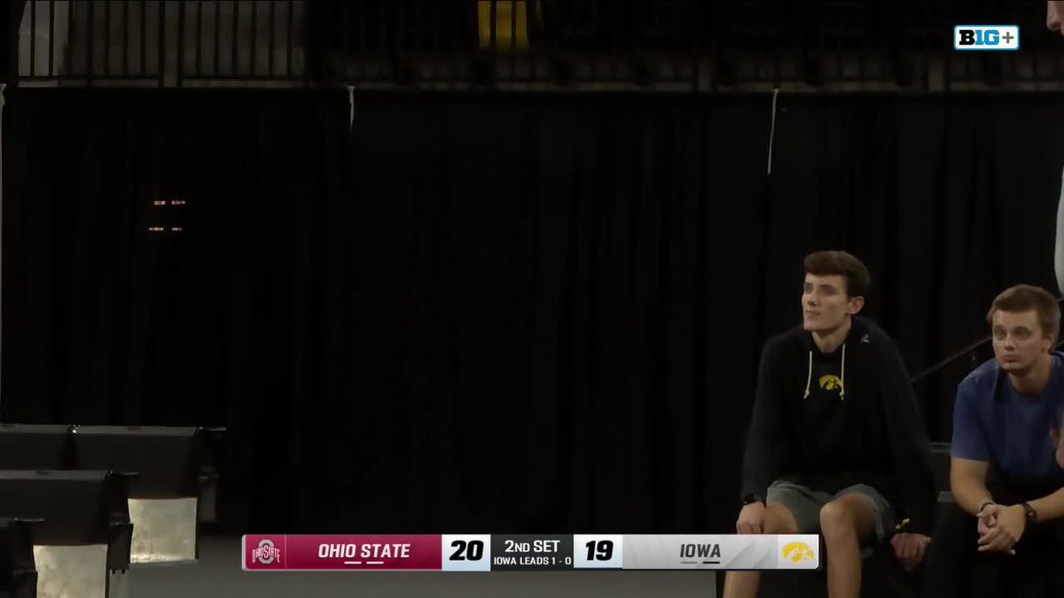 A young man in an Iowa hoodie watches from the sidelines during a volleyball match where Ohio State leads Iowa 20-19 in the 2nd set.