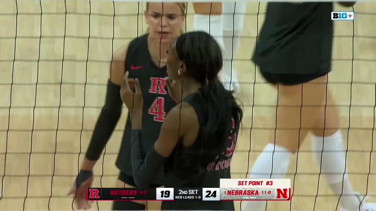 A volleyball match between Rutgers and Nebraska, with a scoreboard showing Rutgers 19, Nebraska 24 in the 2nd Set (Nebraska leads 1-0), and a 'SET POINT #3' graphic displayed. Players in black Rutgers jerseys are visible behind the net.