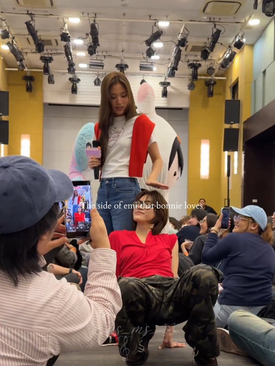 A fan event scene shows a person lying on the floor in a red shirt and camo pants looking up, while another stands holding a microphone with a large mascot character behind them. Text overlay reads 'The side of emi that bonnie loves' and 'shop_lms_pj'.