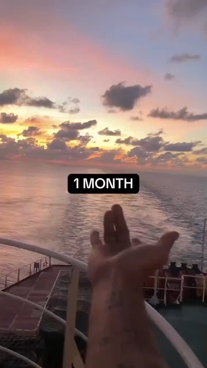 A hand reaching out toward a sunset over the ocean from the deck of a cruise ship, with a '1 MONTH' text overlay in the center.