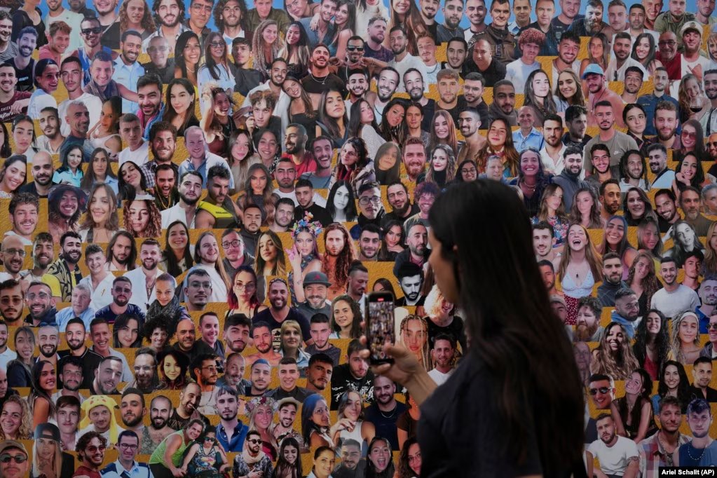 AnastasiosXeno5's tweet photo. @ty_xplorer @MustafaB49 A woman walks past a mural with portraits of victims at the site of the Nova music festival on the one-year anniversary. Do you support Hamas? Why does Turkey finance Hamas? https://t.co/l96d4aUAWP