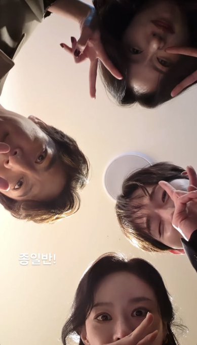 A low-angle shot of four people looking down at the camera making playful faces and peace signs, with Korean text '충일반!' visible.