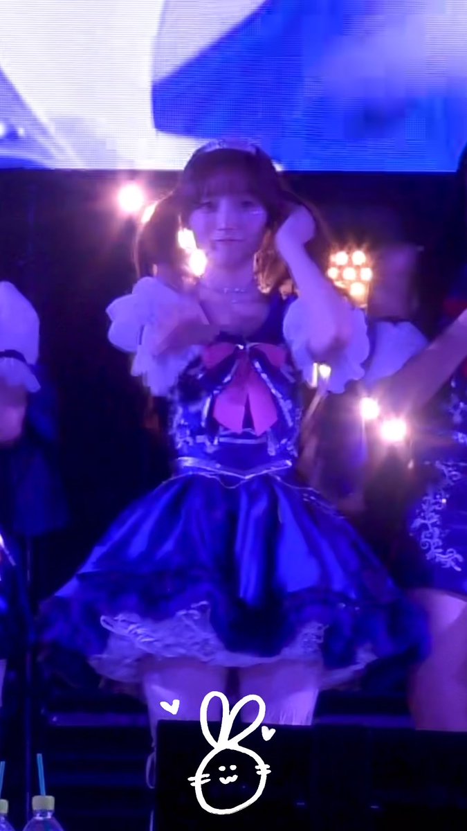 Hina from LIGHTSUM performs on stage in a frilly purple dress at the 260926 SBI Music Circus concert, adjusting her hair under vibrant blue stage lights while promoting their song "Doshite" (#LIGHTSUM_Reidol).