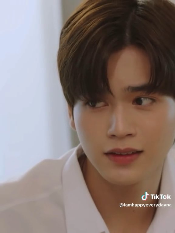 A close-up of a young man with brown hair and dreamy eyes, wearing a white shirt, looking slightly to the side with a soft expression. The TikTok watermark "@iamhappyeverydayna" is visible, matching the caption's affectionate description of his cute, captivating gaze.