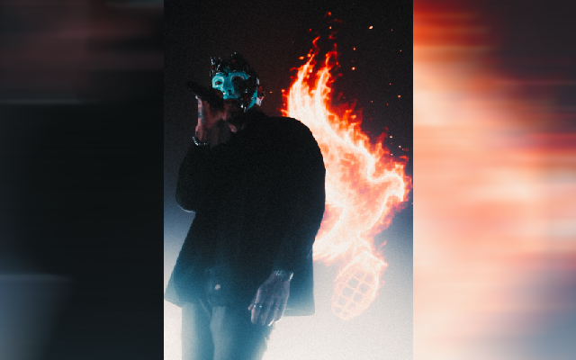 A masked performer, presumably from Hollywood Undead, sings into a microphone while dramatic flames burst behind them on stage, perfectly capturing the "masks" and theatrical energy mentioned in the Taste of Chaos Tour post.