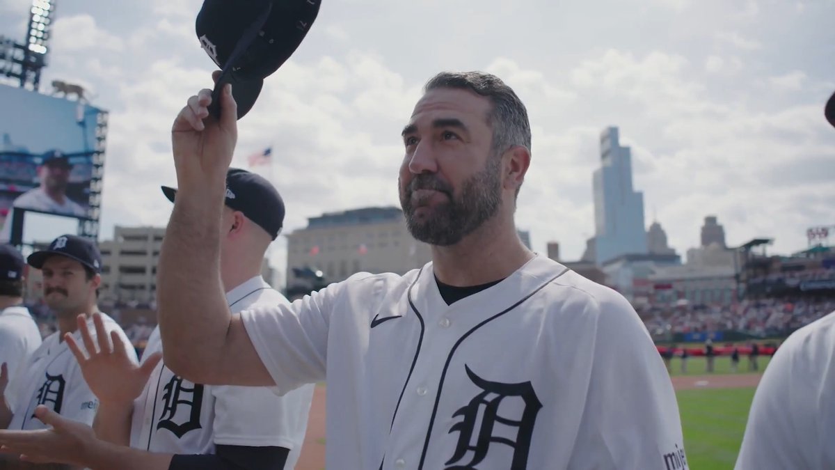 A Detroit Tigers player, identifiable by the "D" logo on his white jersey, tips his cap while standing on the field at a baseball stadium with a city skyline in the background. The image captures a moment of appreciation from the crowd, reflecting the post's message about Justin Verlander's lasting impact and character beyond his on-field performance.