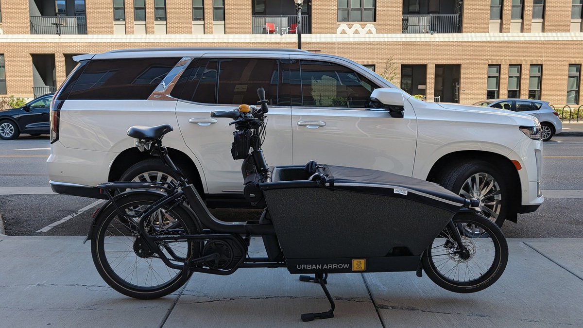 AmericanFietser's tweet photo. One of these is an oversized, elitist mobility vehicle. The other is an e-cargo bike. One tears up our local infrastructure and is a threat to people outside of it. The other weaves into the urban fabric, accomplishing a lot and asks for very little. https://t.co/bbXqa1tGFK