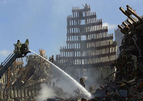 25YearsAgoLive's tweet photo. Firefighters spray a smoldering blaze at Ground Zero, which is still on fire 15 days after the September 11 attacks, making conditions dangerous for recovery workers. https://t.co/b32QdxleLt
