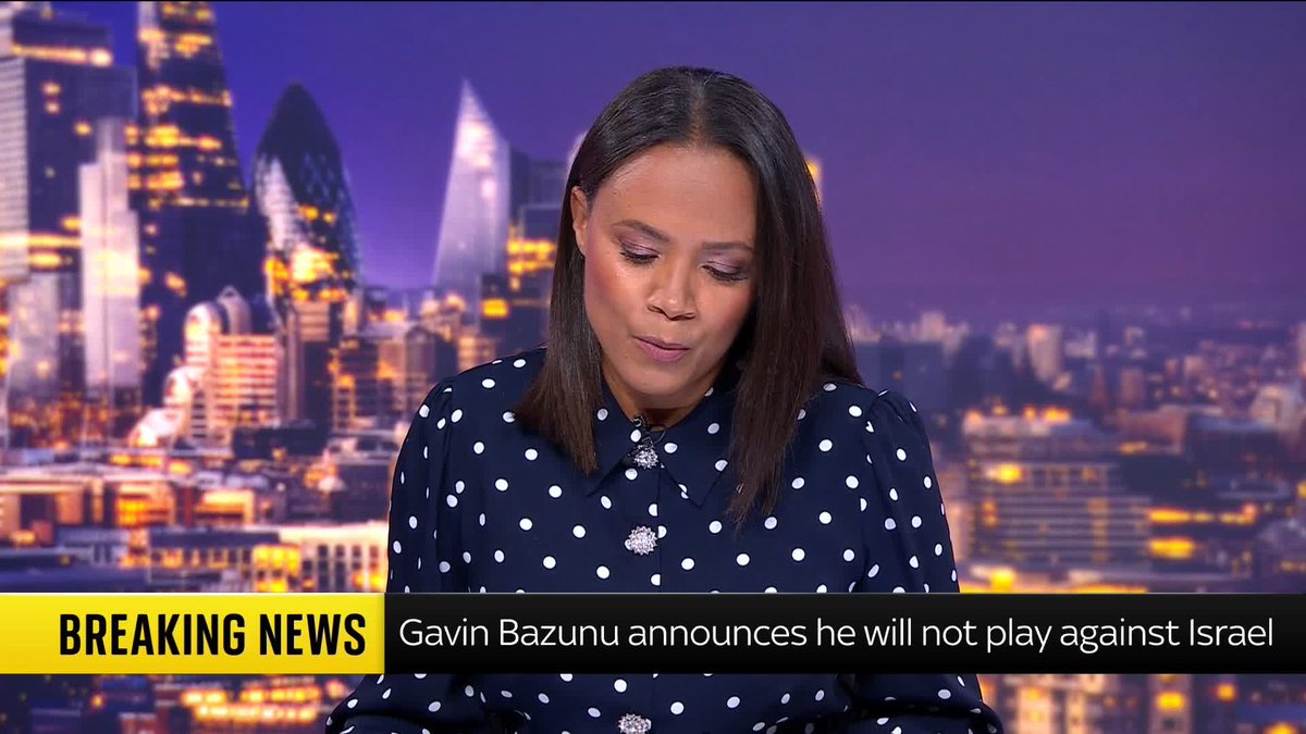 A news presenter in a polka-dot blouse delivers breaking news in front of a nighttime city skyline backdrop. The on-screen chyron reads "BREAKING NEWS: Gavin Bazunu announces he will not play against Israel," corresponding with the report about the Republic of Ireland goalkeeper declaring he will not participate in upcoming Nations League fixtures against Israel due to the ongoing conflict in Gaza.