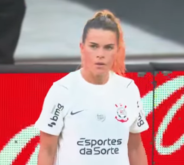 A female soccer player wearing a white Corinthians jersey with "Esportes da Sorte," "bmg," and the club crest visible stands on the field, with the Portuguese word "MÃE" (meaning "mother") suggesting a tribute to her role as a mother.