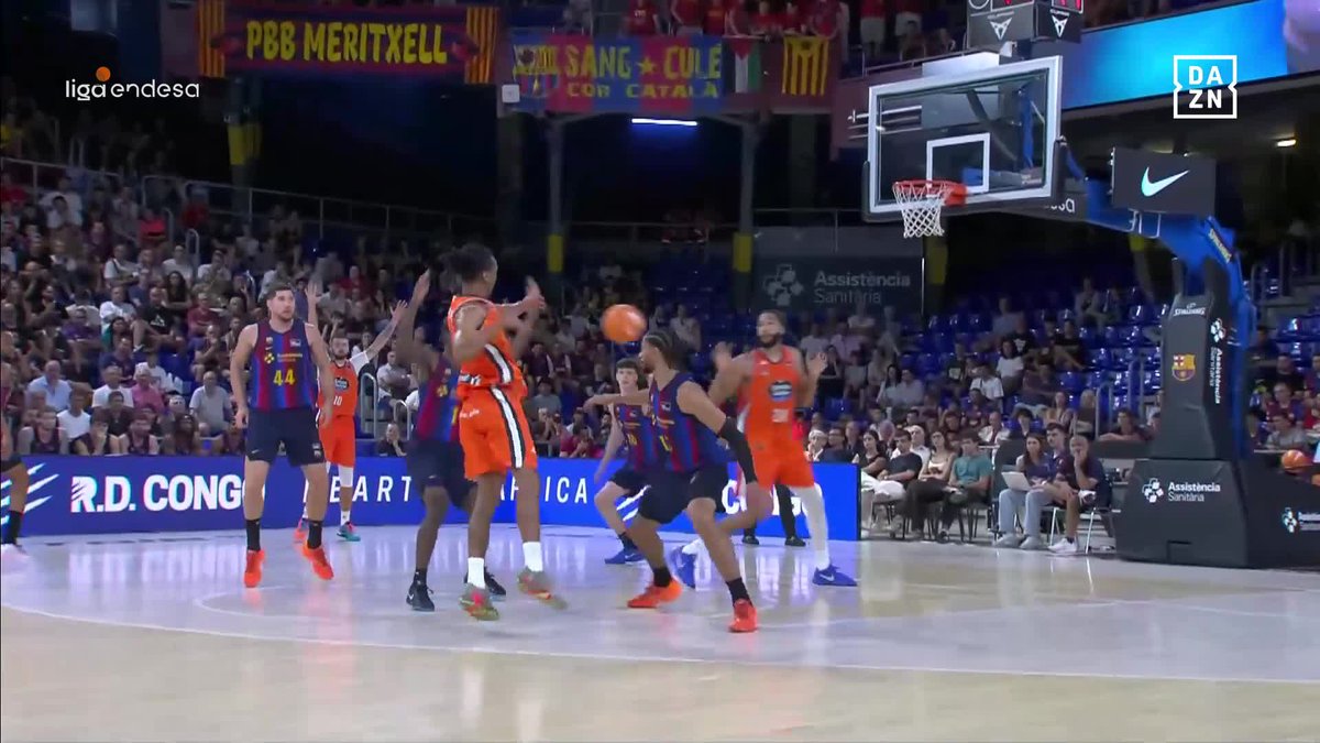 A basketball game is underway with players in orange and blue/red striped jerseys near the hoop, with the ball in mid-air during play. Visible text includes "liga endesa," "PBB MERITXELL," "DAZN," and "Assistencia Sanitaria," suggesting this is a Liga Endesa match broadcast on DAZN.