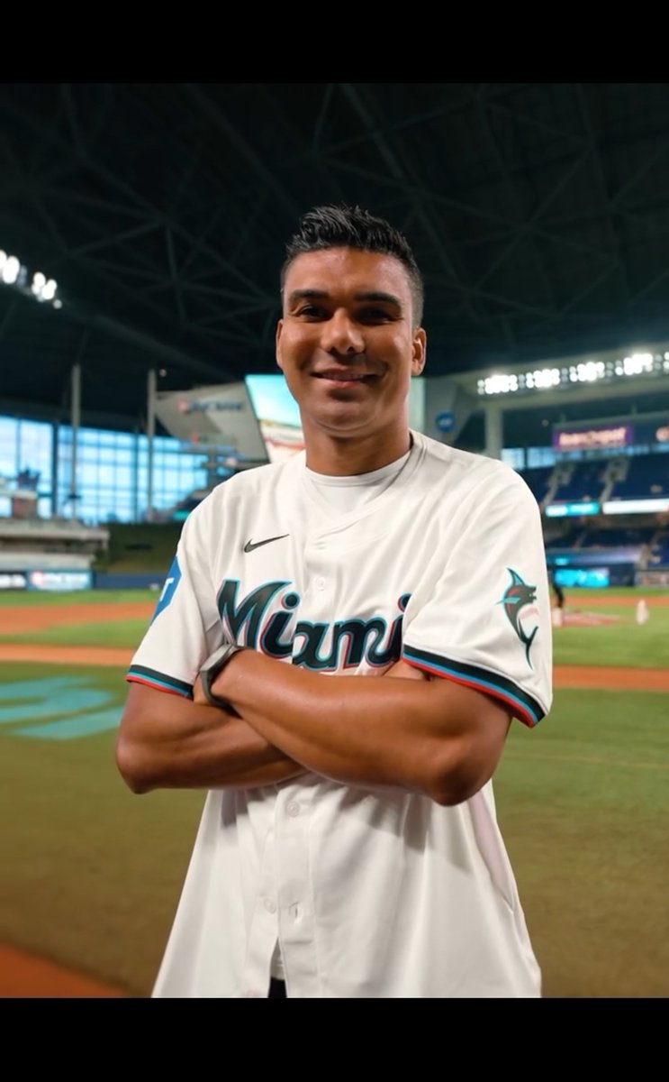 A smiling man poses on a baseball field wearing a white Miami Marlins jersey with arms crossed, thanking the Marlins organization as indicated in the post caption.