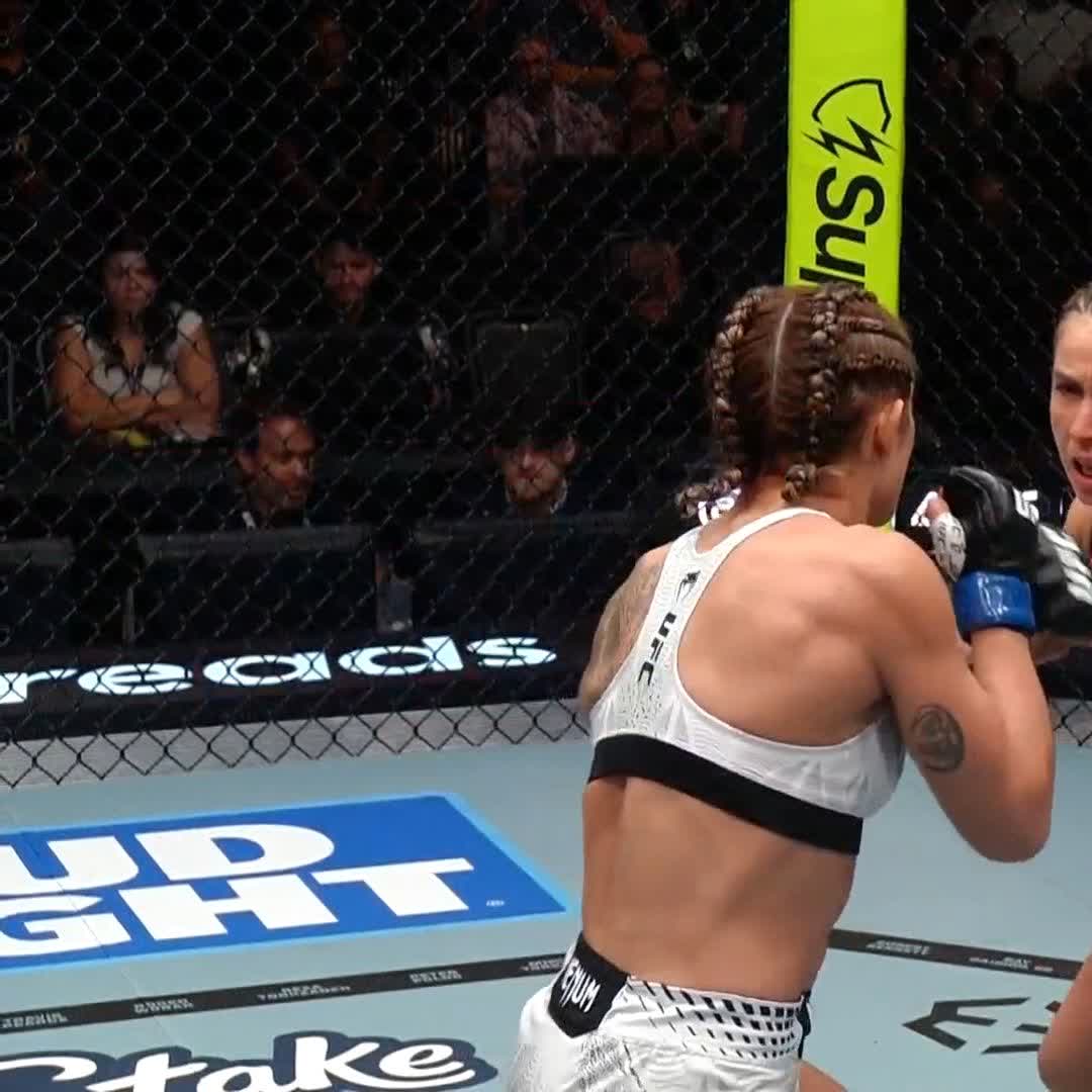 Two female UFC fighters clash inside the octagon, with "BUD LIGHT" and "Stake" branding visible on the mat and a partially visible yellow banner on the cage, capturing a moment from the UFC Vegas 121 event where Yazmin Jauregui scored a first-round knockout of Vanessa Demopoulos.