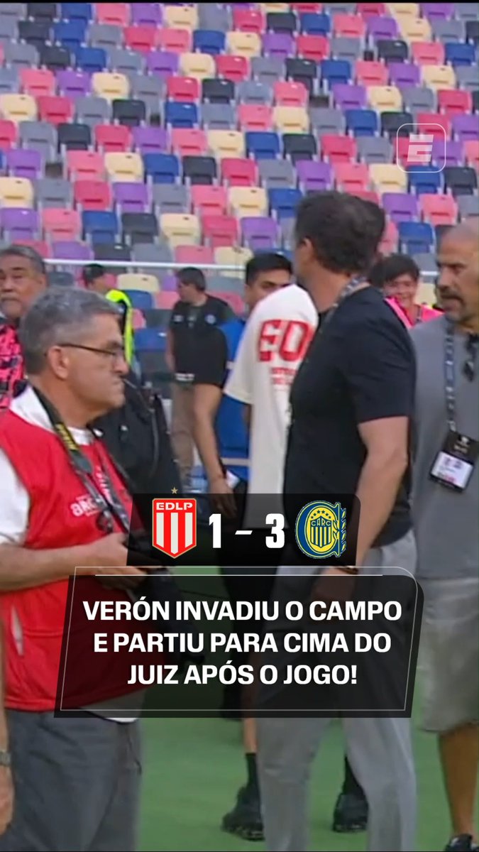 The image shows a post-match confrontation in a stadium with colorful empty seats, featuring a scoreboard displaying "EDLP 1-3" alongside the Rosario Central logo. Text overlay reads "VERÓN INVADIU O CAMPO E PARTIU PARA CIMA DO JUIZ APÓS O JOGO!" illustrating the post about Estudiantes president Verón storming the field to confront the referee following his team's 3-1 loss to Rosario Central in the Supercopa Internacional.