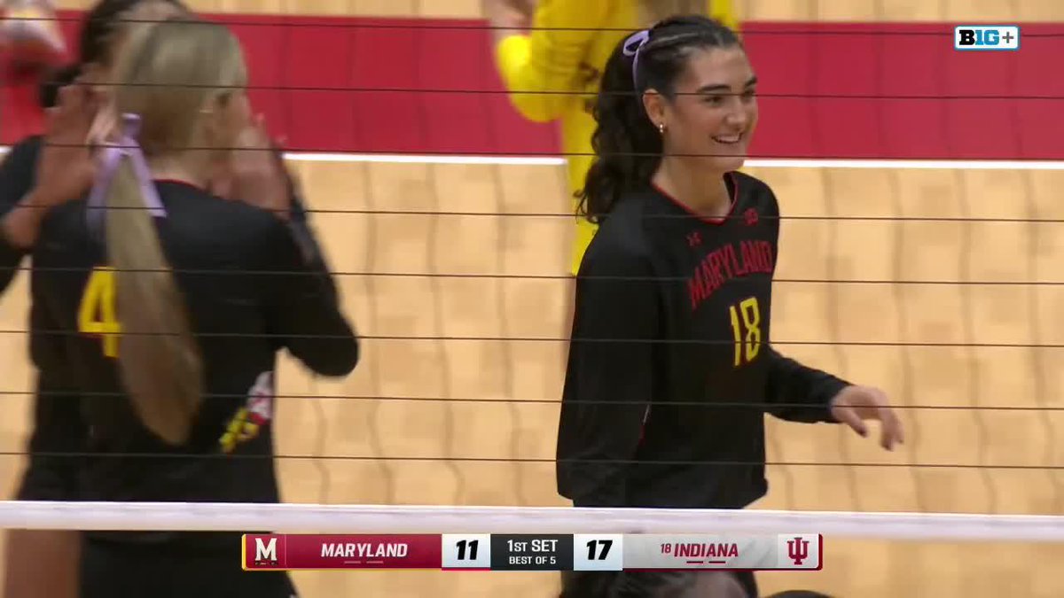 A Maryland volleyball player wearing jersey #18, smiling broadly, is seen on the court during a Big Ten match against Indiana, where Indiana leads 17-11 in the first set of a best-of-5 game. The caption "YEAH SARA" suggests the player pictured is Sara, likely celebrating a successful play.