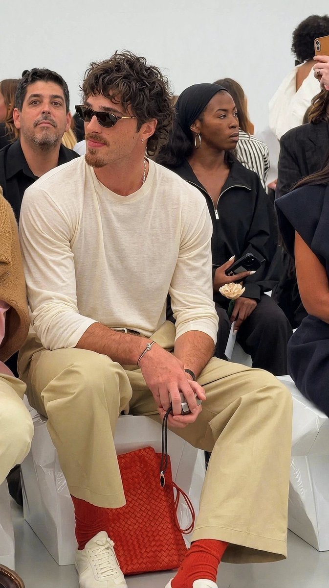 popbuzzz_'s tweet photo. Jacob Elordi steals the show sitting in the front row at Bottega Veneta’s Spring/Summer 2027 show wearing a white long-sleeve shirt, beige trousers, red socks, and the brand’s signature red woven bag. https://t.co/DY7NkNUcJs