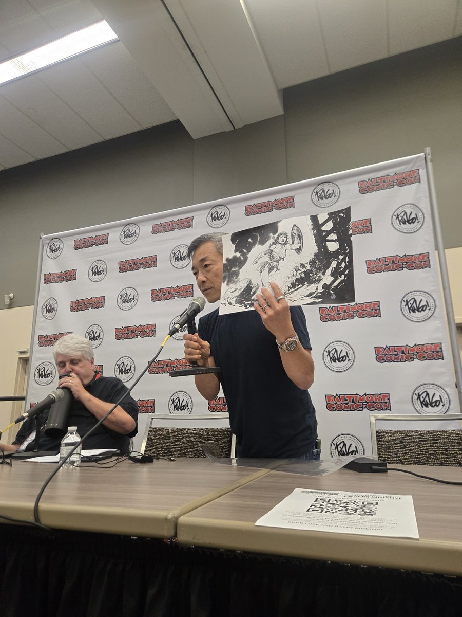 heroinitiative's tweet photo. @JimLee's TNT movie promo art piece brought in $9,000 at our Baltimore Comic-Con auction! (And yes, that’s Jim himself guest auctioneering in the photo!)

Thank you to Jim and the winning bidder for showing up for comic creators in need. #BeTheHero #BCC2026 https://t.co/Tgp6I6Yn9A