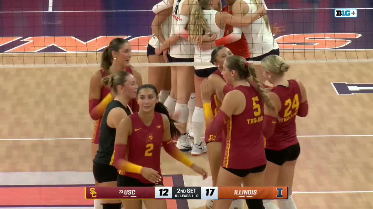 USC and Illinois women's volleyball players gather near the net during a match, with the scoreboard showing USC at 12 and Illinois leading 17 in the 2nd set.