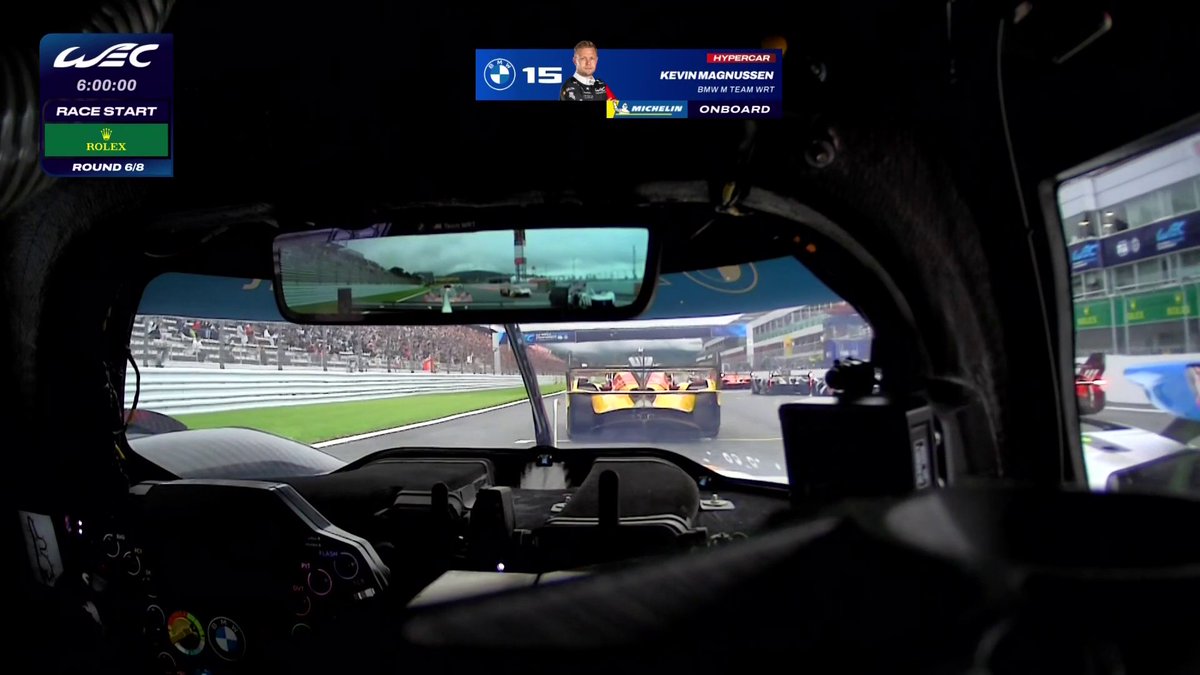 An onboard camera perspective from Kevin Magnussen's #15 BMW M Team WRT Hypercar shows the starting grid moments before the race begins at the WEC 6 Hours of Fuji, displaying "RACE START" at 6:00:00 on Round 6/8.

The image directly relates to the post by capturing the highly anticipated race start moment from a driver's eye view, providing fans an immersive look at the beginning of the 6 Hours of Fuji endurance race.
