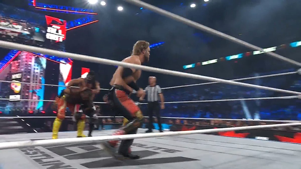 WWE wrestlers compete in a ring during a match, with a 'BRAWL OUT' graphic visible on the screen and a referee observing the action in the arena.