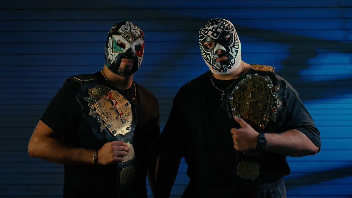 Two luchadores wearing traditional Mexican wrestling masks stand side by side against a blue background, each proudly holding a championship belt over their shoulder. The accompanying post indicates they are the Wagner Brothers, a tag team aiming to win the Dusty Rhodes Tag Team Classic on the AAA en Fox event.